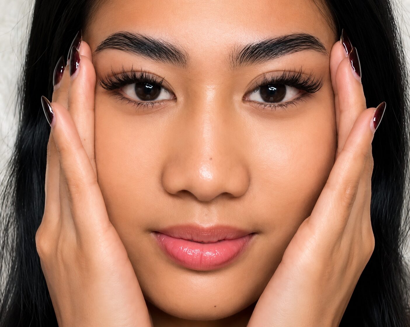 Close-up of luxury false eyelash extensions on pink silk with a gold tweezer